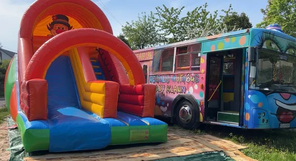 Dmuchana zjeżdżalnia z klaunem obok Wesołego Autobusu